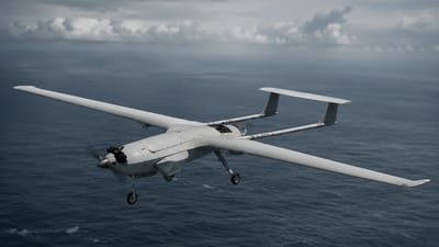 A fixed-wing uncrewed aircraft on patrol over open ocean beneath an overcast sky.