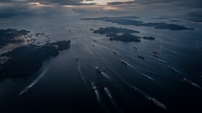Aerial view of an Indo-Pacific shipping lane at dusk, vessels underway between islands.
